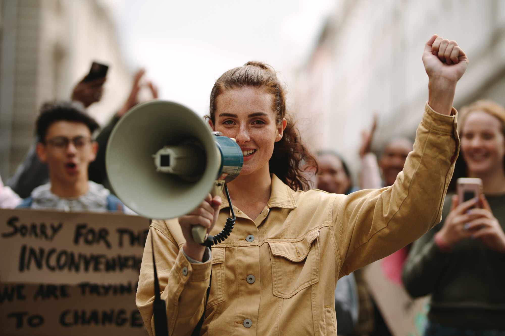 Modern urban woman protesting at a strike yelling her grievances into a megaphone. Female activist protesting with megaphone during a strike.